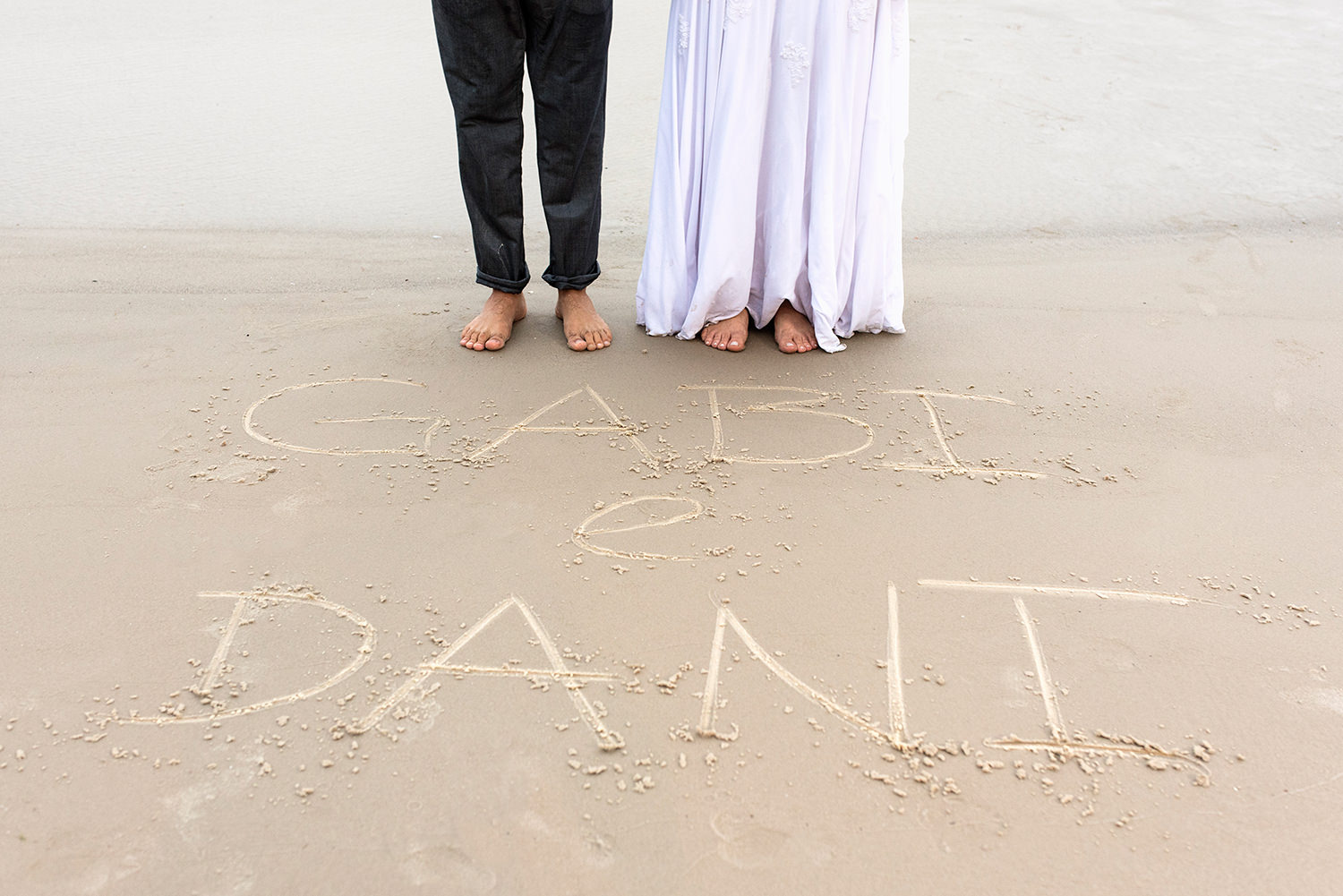 Bride and groom name written at the sand